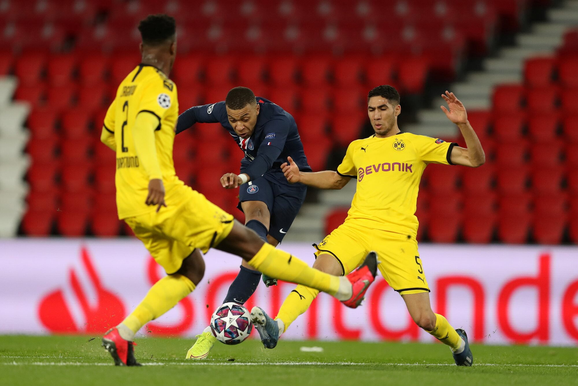 Paris Saint-Germain's Kylian Mbappé battles for the ball against Borussia Dortmund's Achraf Hakimi and Dan-Axel Zagadou